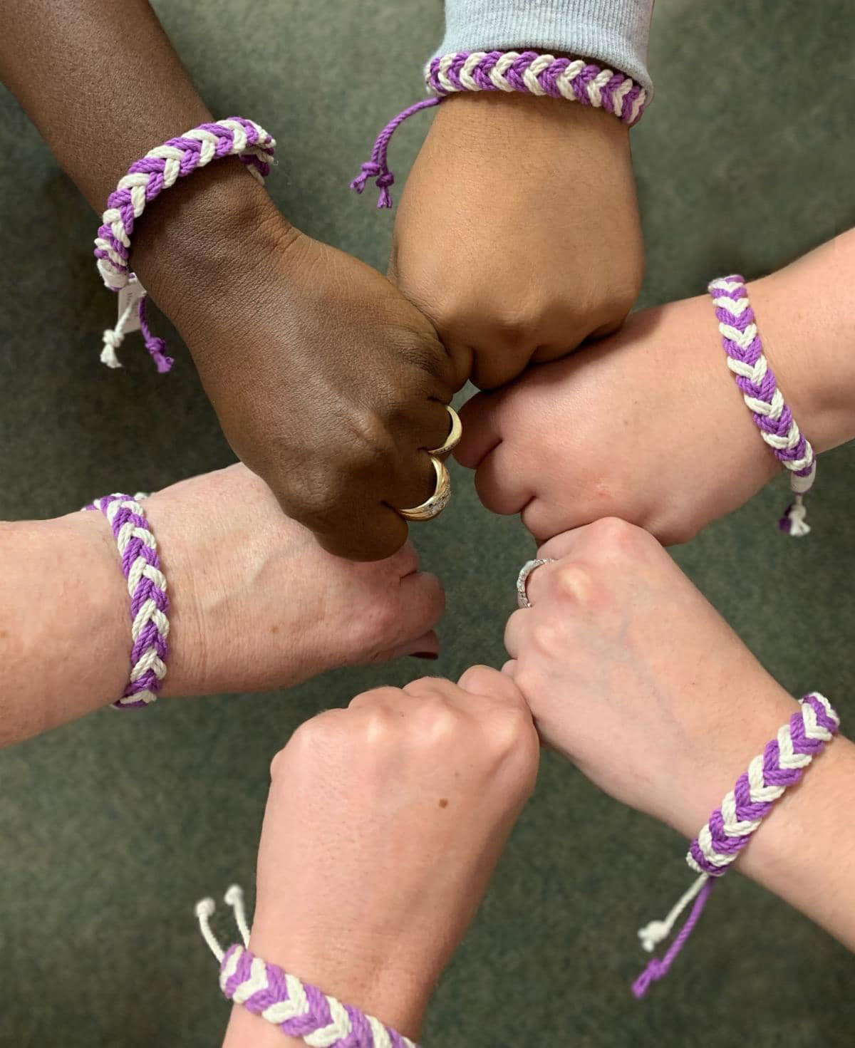5 Hands with Purple Bracelets unified in a circle