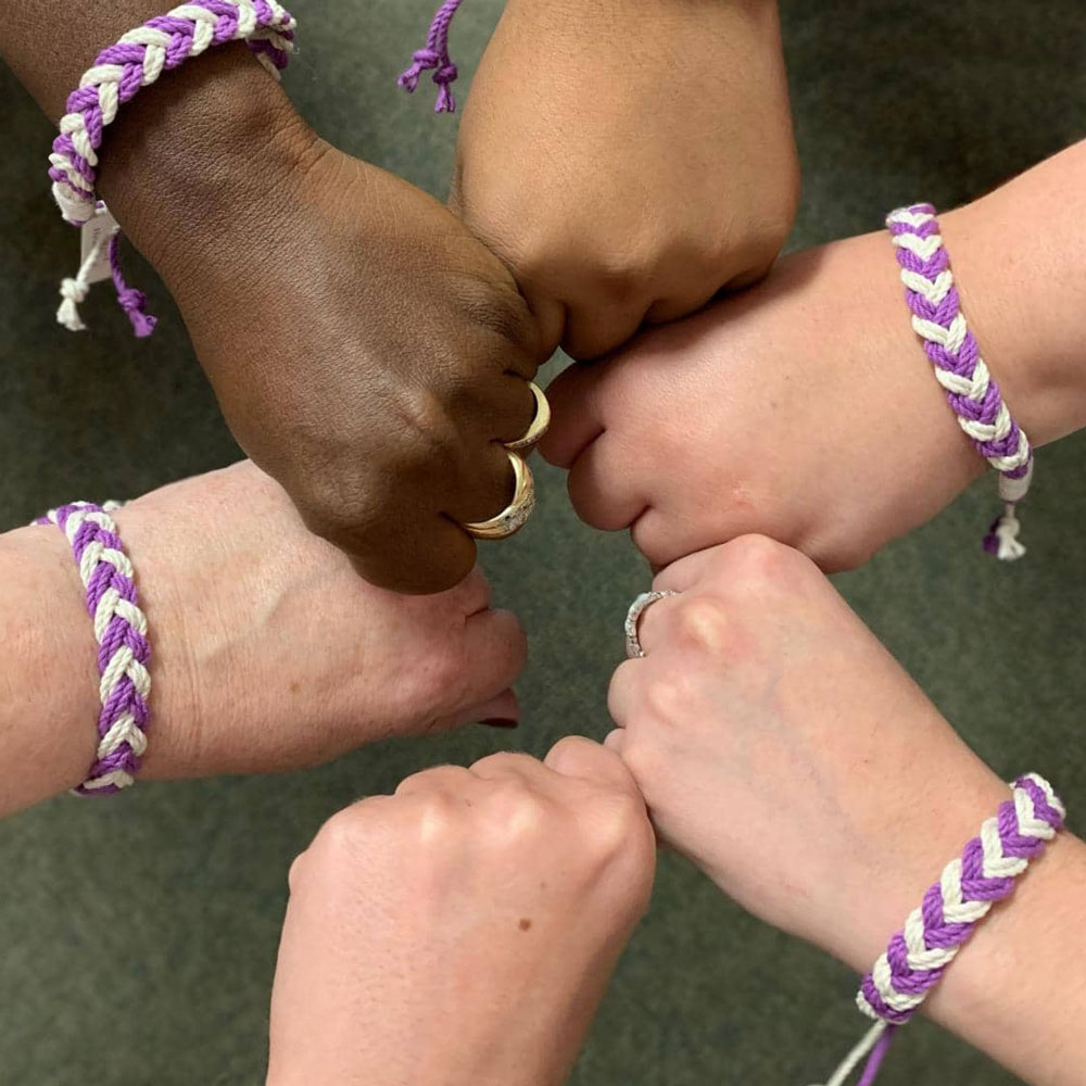 5 Hands with Purple Bracelets unified in a circle
